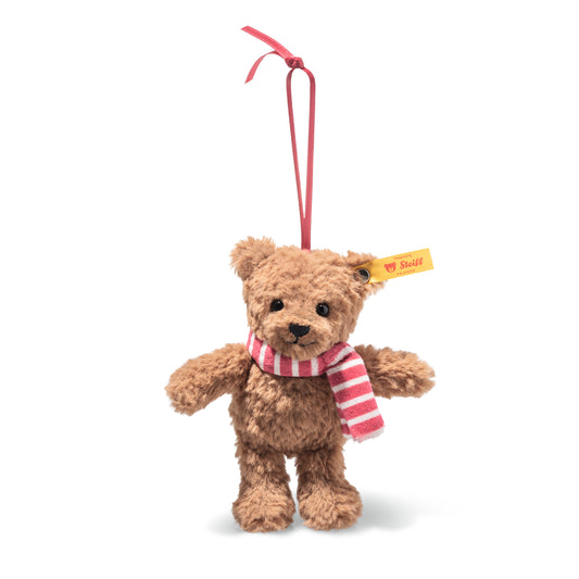 This is Ben by Steiff. Small teddy named Ben sits upright with soft, medium-length curly fur that has a matte sheen. The fur is brown overall; the muzzle is brown with a distinct black triangular nose and a stitched black mouth, the eyes are black and round, the ears are brown, the tummy is brown, the paws are brown and the paw pads match the brown fur. No separate markings are visible. Ben wears a striped scarf in alternating pink and white bands with a soft knitted look and hangs from a narrow ribbon...