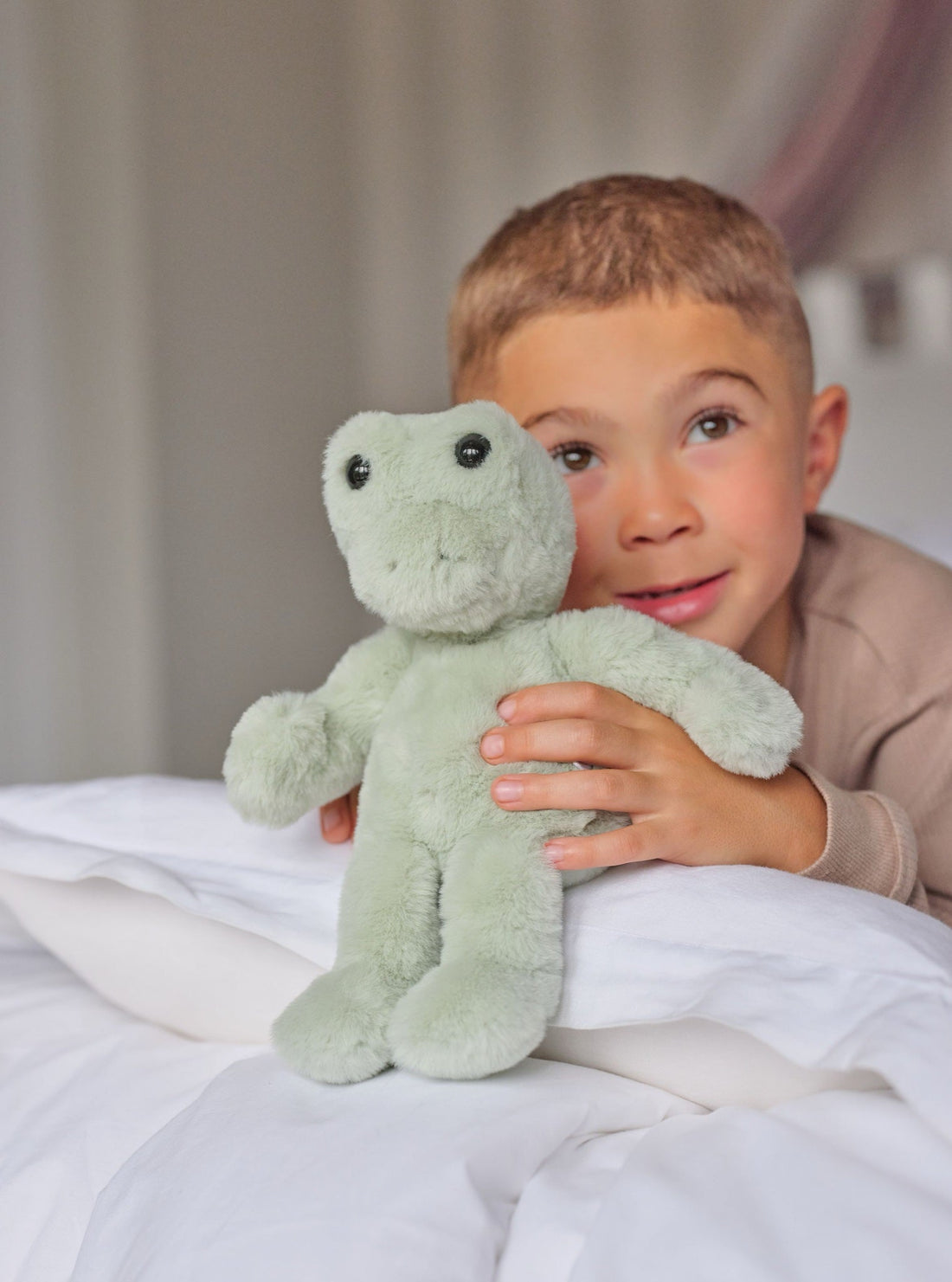 Boy holding Freddie Frog on the bed